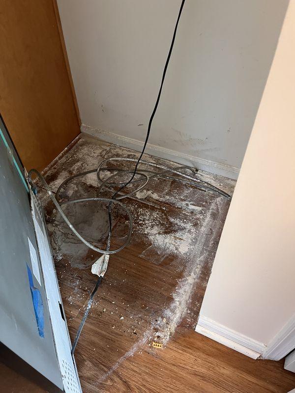 Before: the floor behind a fridge before cleaning